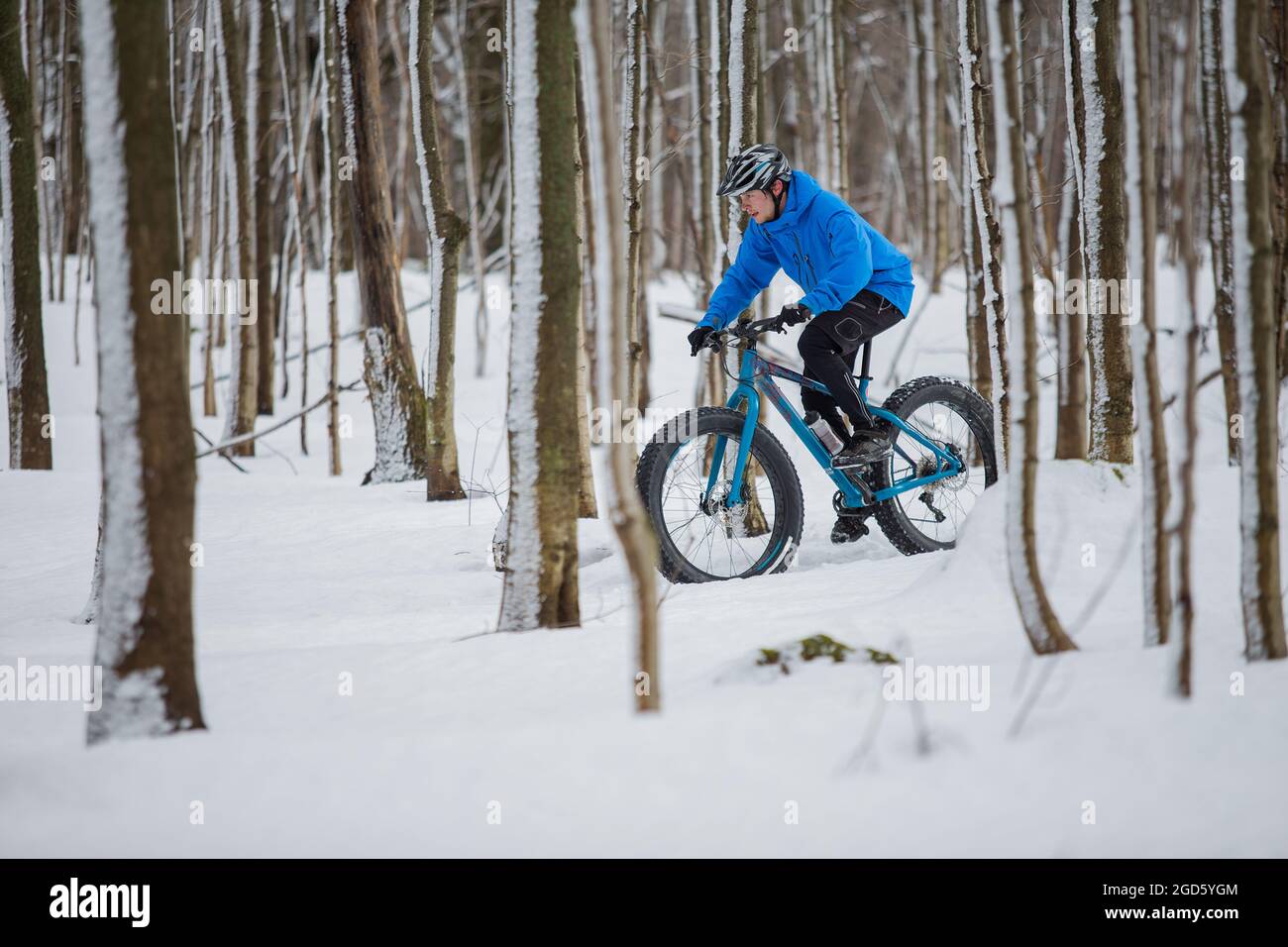 Uomo che cavalca la sua bici grassa nella neve Foto Stock