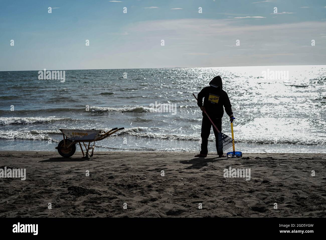 Makassar, Sulawesi del Sud, Indonesia. 11 Agosto 2021. Un gianitore pulisce i rifiuti su una spiaggia a Makassar City, Sulawesi del Sud, Indonesia. Anche se è ancora nel periodo pandemico, la pulizia della spiaggia è ancora mantenuta in modo che rimane pulito e bello per il pubblico di visitare. (Credit Image: © Herwin Bahar/ZUMA Press Wire) Foto Stock