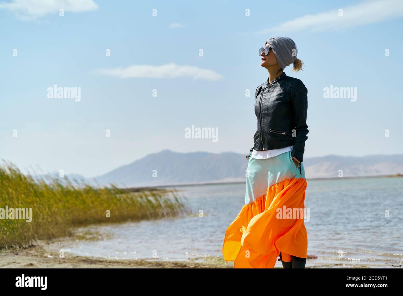 donna turistica asiatica in piedi presso un lago che guarda la vista sotto il cielo blu Foto Stock
