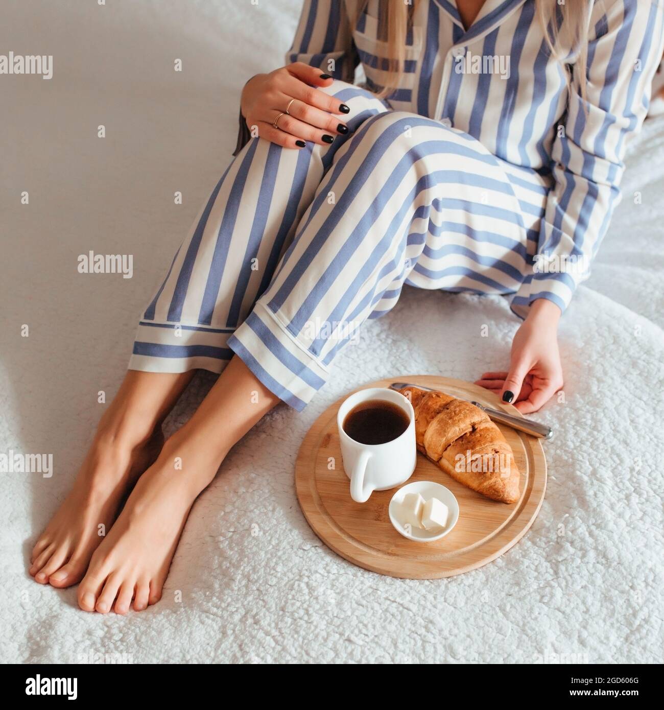 le belle gambe delle donne in pigiama e accanto ad un caffè con un  croissant. il concetto di caffè a letto Foto stock - Alamy