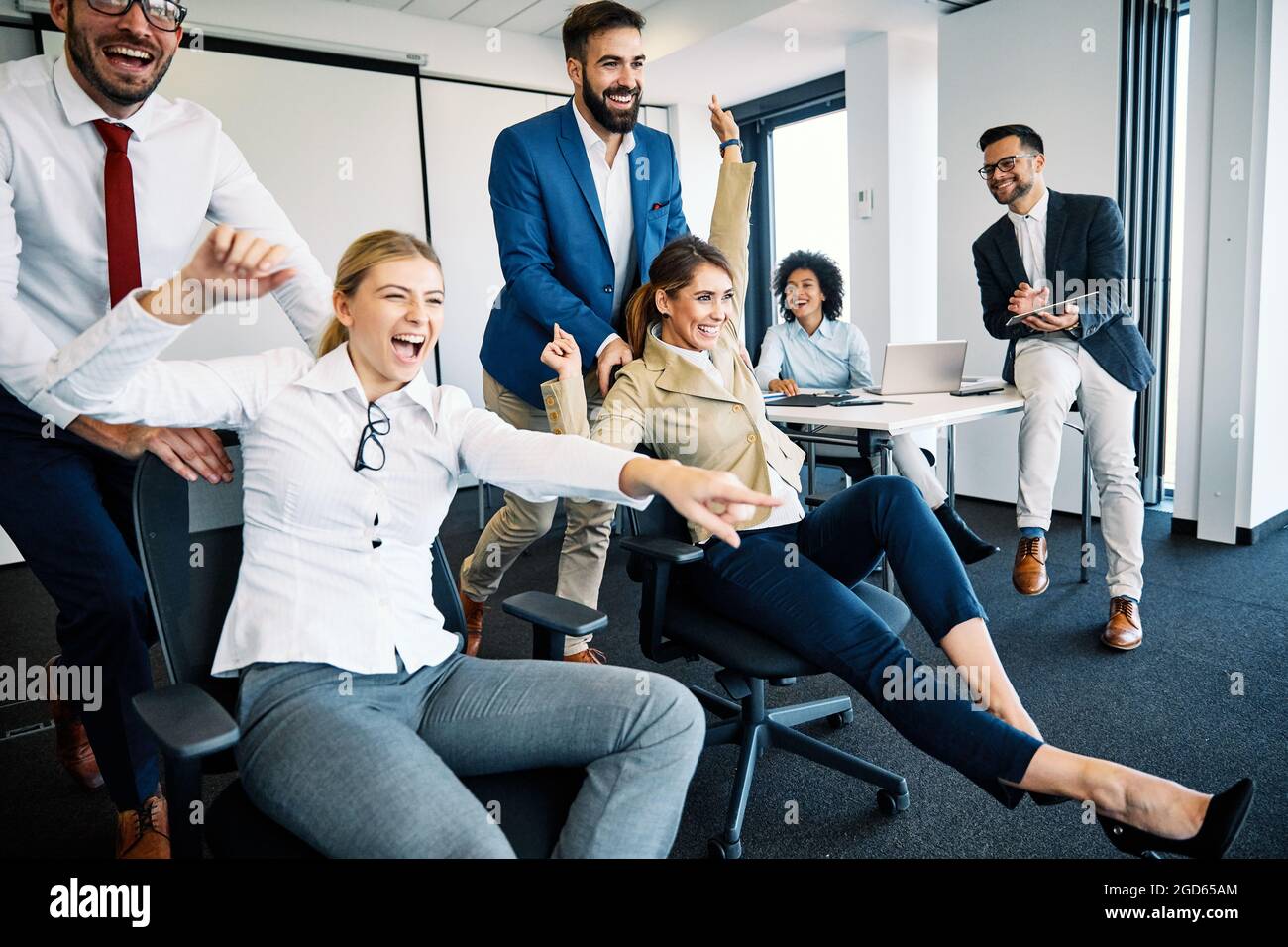 ufficio giovani uomini d'affari che prendono umorismo abreak spingendo sedie Foto Stock
