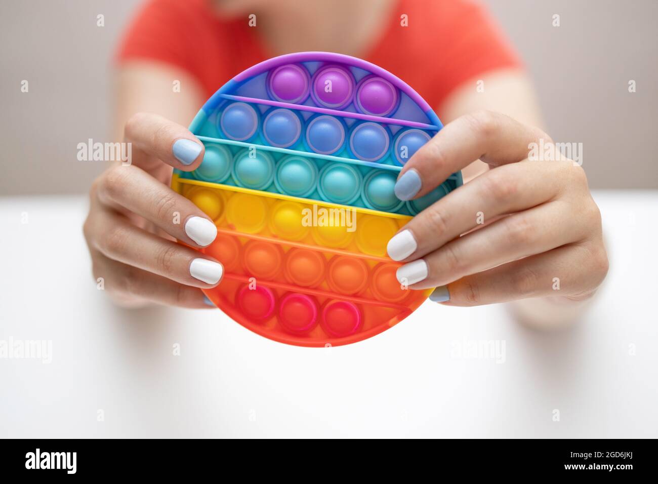 Il fidget sensoriale arcobaleno isolato in mano su sfondo bianco. Nuovo giocattolo alla moda in silicone. Foto Stock