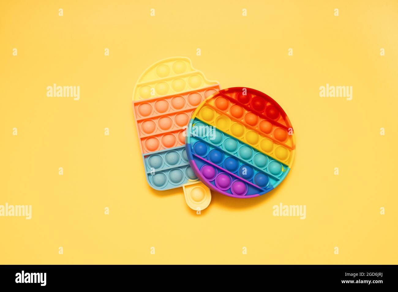 Giocattoli sensoriali colorati anti-stress pop IT per bambini su sfondo giallo Foto Stock