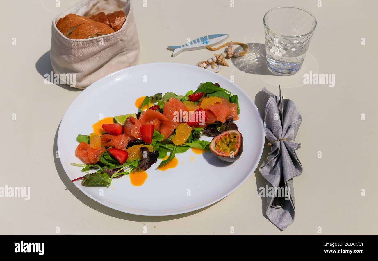Insalata di valax al salmone con frutto della passione e fragole, piatto bianco. Foto Stock