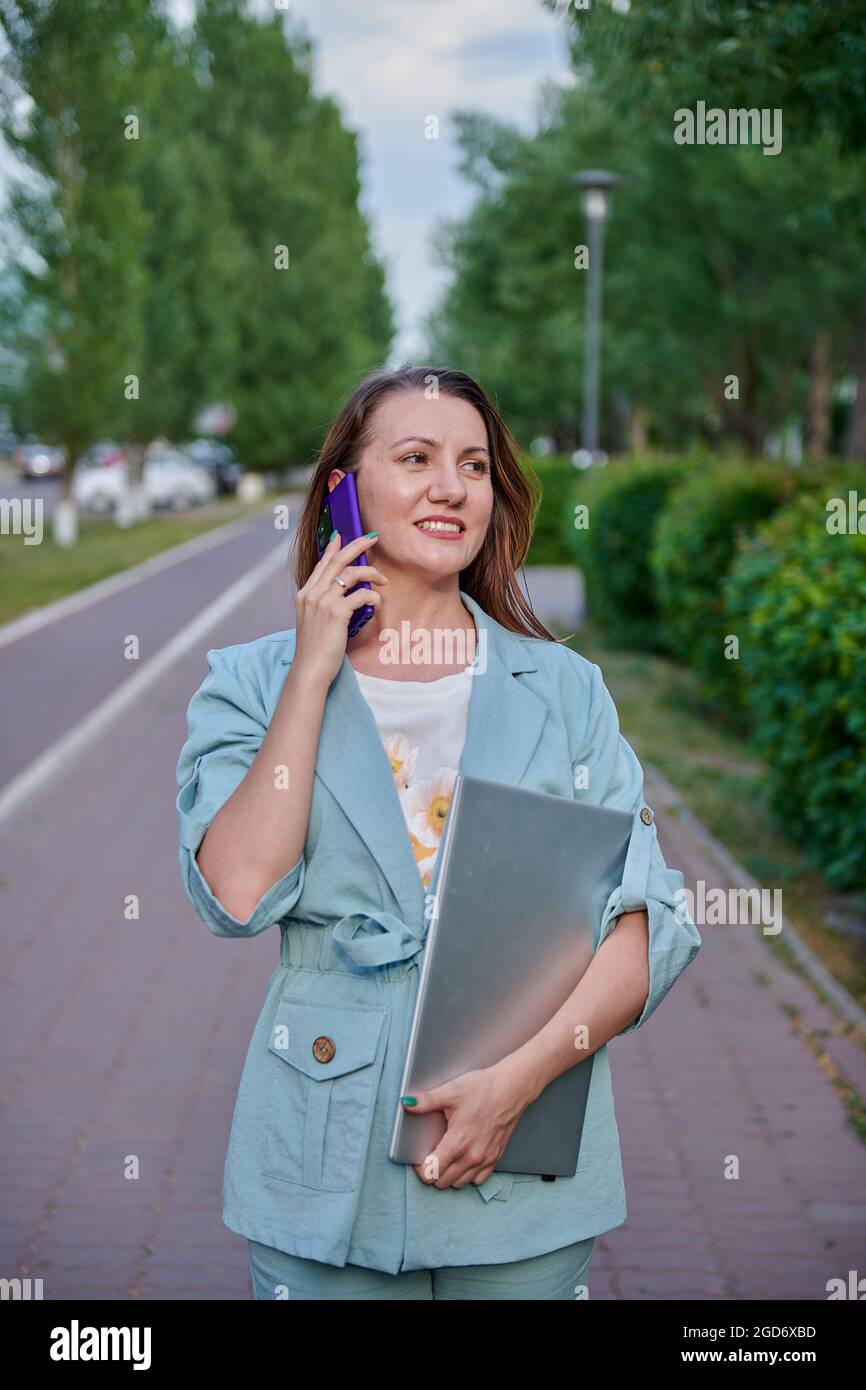 una ragazza che cammina per la città con un computer portatile Foto Stock