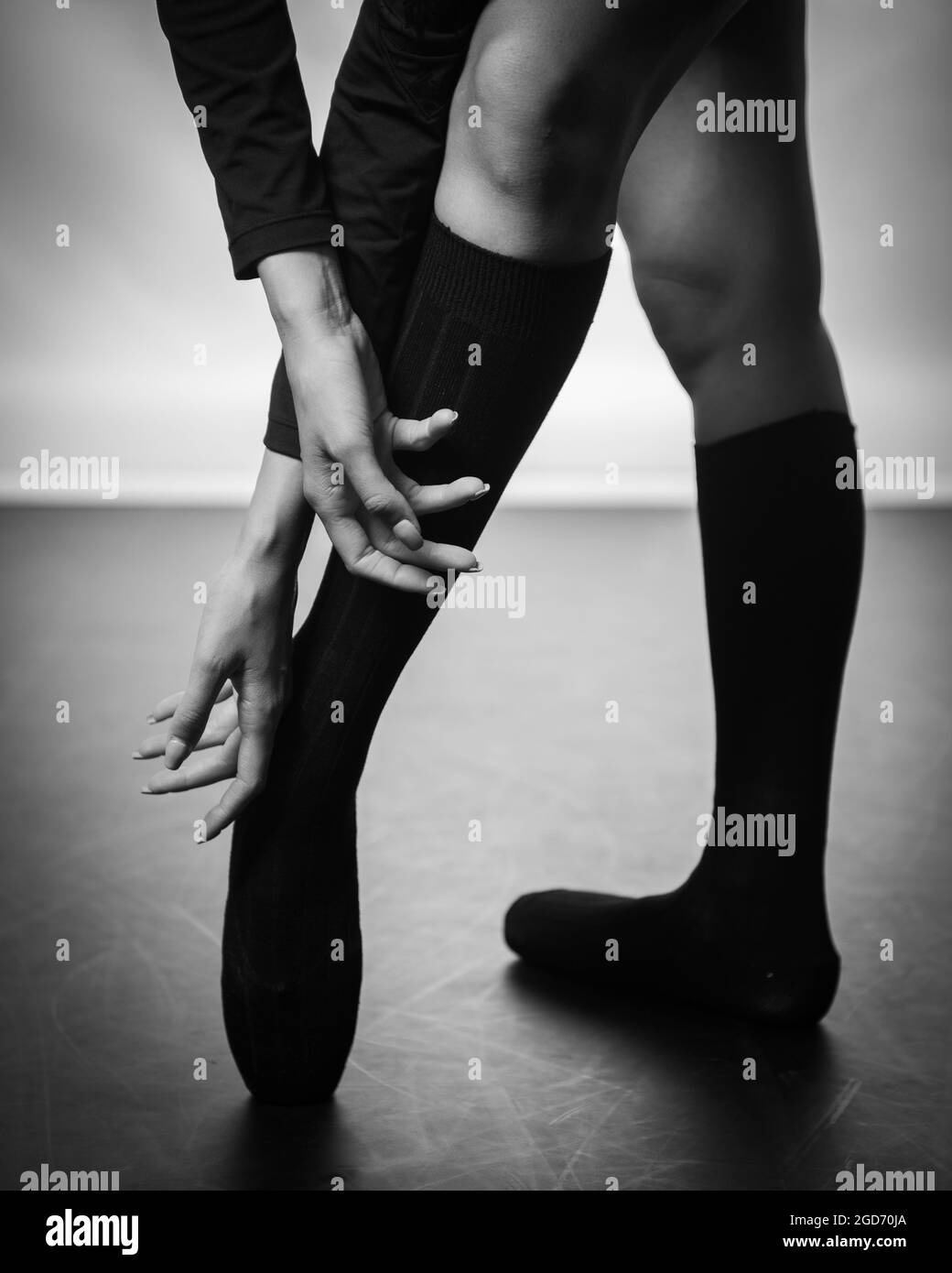 Gambe di ballerina giovane con scarpe da punta che ballano su uno sfondo a pavimento nero. Pratica di balletto. Piedi di ballerina. Foto Stock