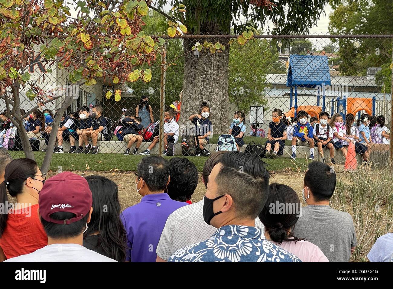 La gente guarda mentre gli studenti arrivano per il primo giorno di scuola alla scuola elementare di Brightwood, mercoledì 11 agosto 2021, a Monterey Park, Calif. Foto Stock