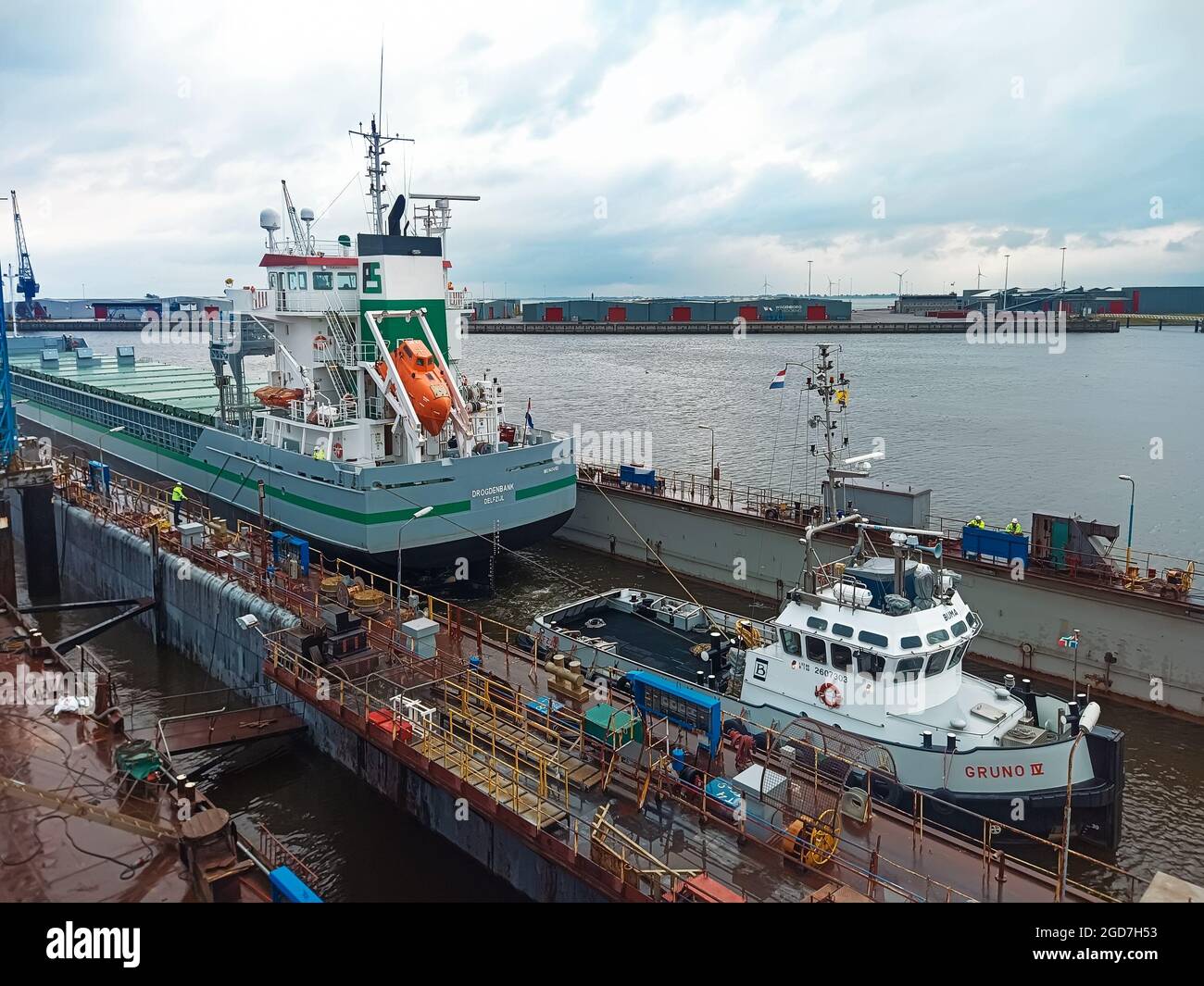 07.31.2021 Paesi Bassi, Delfdzijl A Tug tira una nave da carico a secco per le riparazioni in un cantiere navale. Traino di un'imbarcazione da trasporto mediante rimorchiatore per la riparazione a d Foto Stock