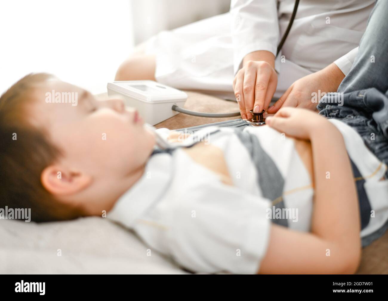 Il bambino è un paziente e un medico. Misurazione della pressione sanguigna con un tonometro. Foto Stock