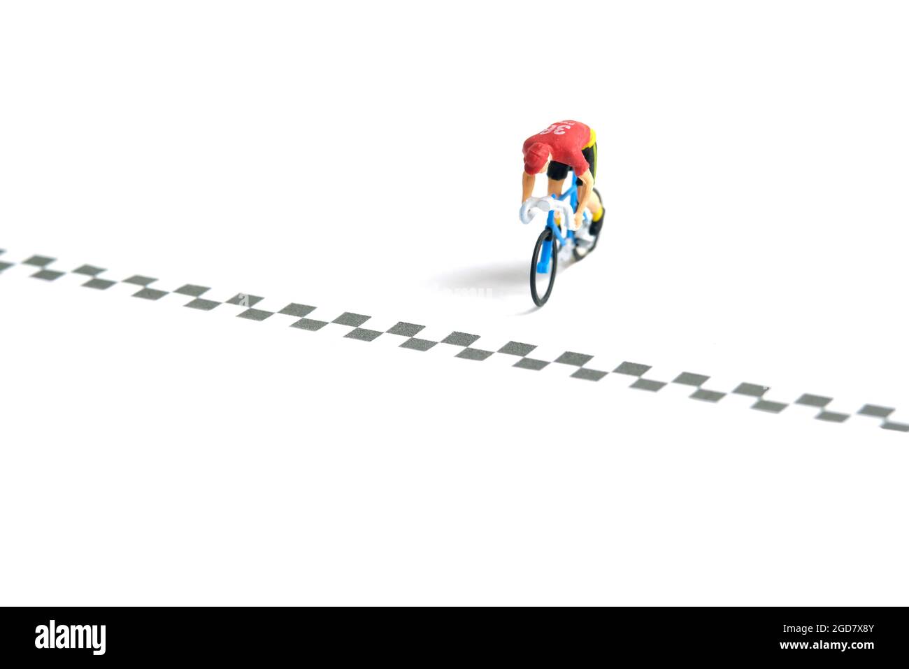 Foto di personaggi giocattolo in miniatura. Un biker con linea di arrivo, ha completato la gara di moto, isolato su sfondo bianco. Foto immagine Foto Stock