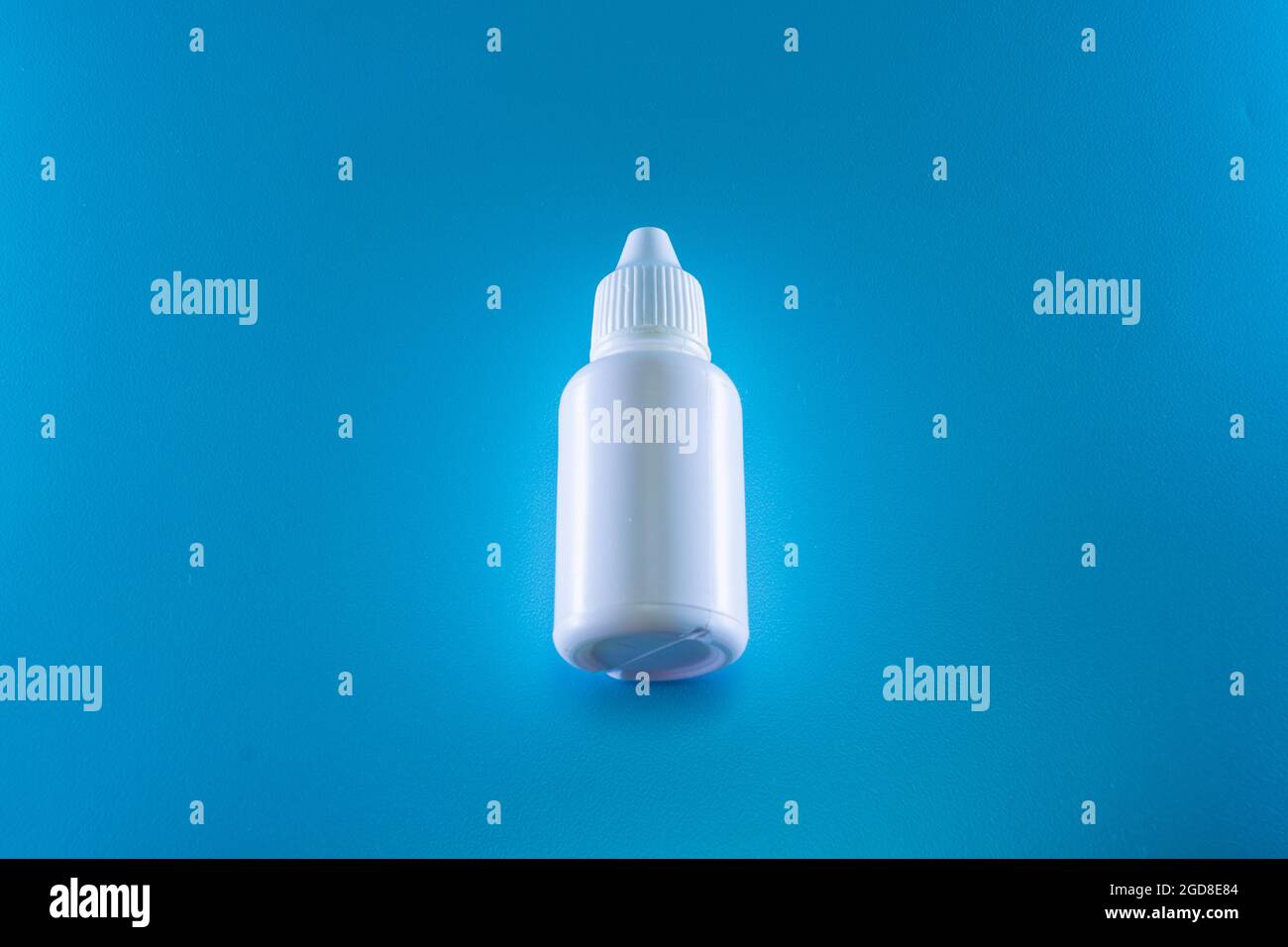 Bottiglia di gocce bianche su sfondo blu Foto Stock