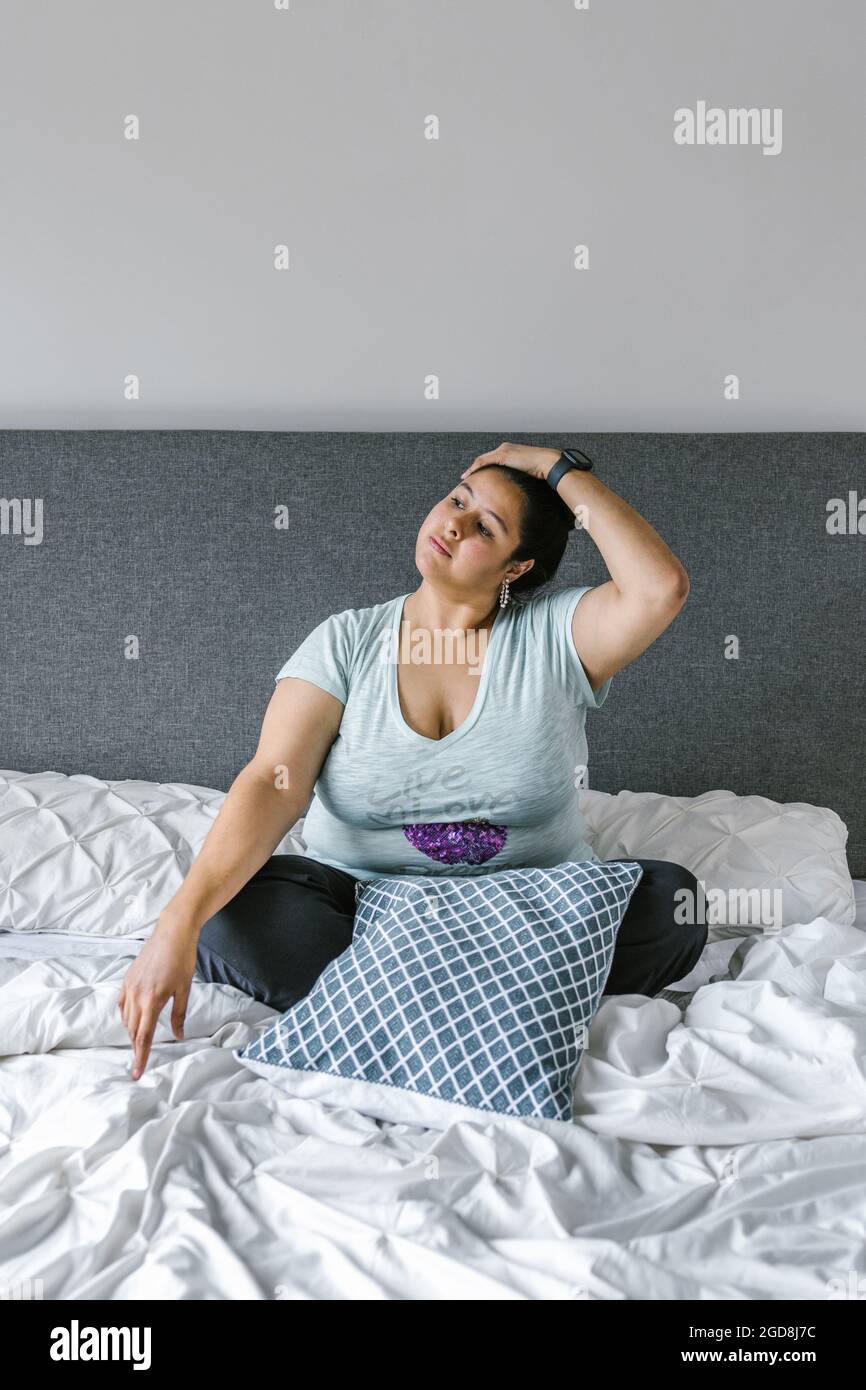 ragazza latina più collo rilassante seduta sul letto in America Latina, più la taglia donna Foto Stock