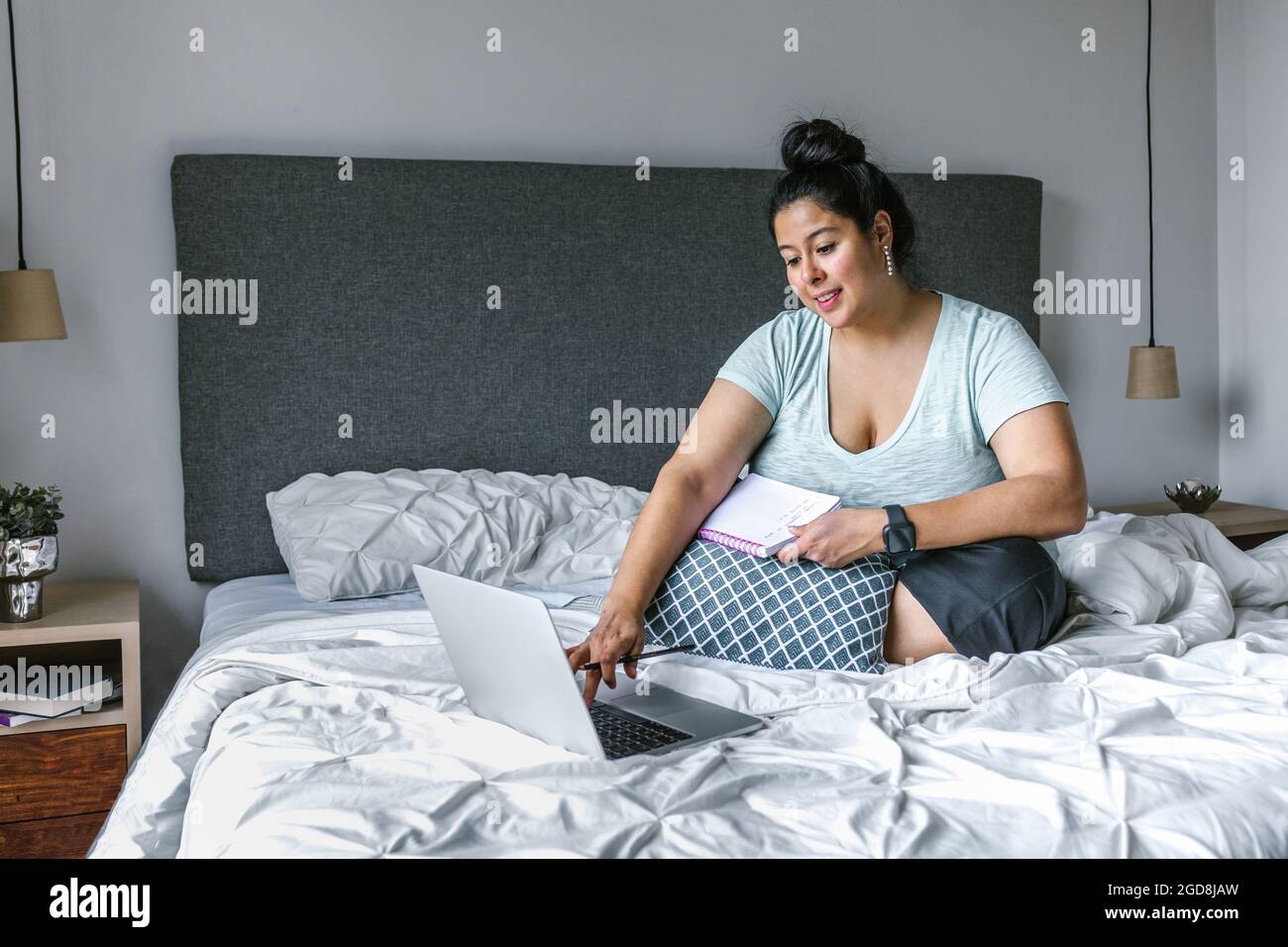 Più ragazza latina di formato che lavora su laptop in camera da letto in America Latina, più donna di taglia Foto Stock