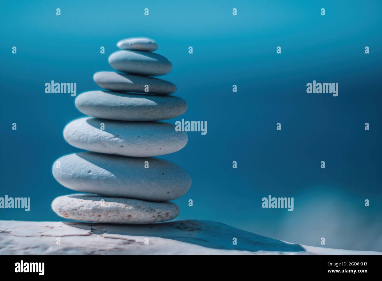 Equilibrata piramide di ciottoli sulla spiaggia in una giornata di sole. Abstract Sea bokeh sullo sfondo. Messa a fuoco selettiva. Pietre Zen sulla spiaggia di mare, meditazione Foto Stock