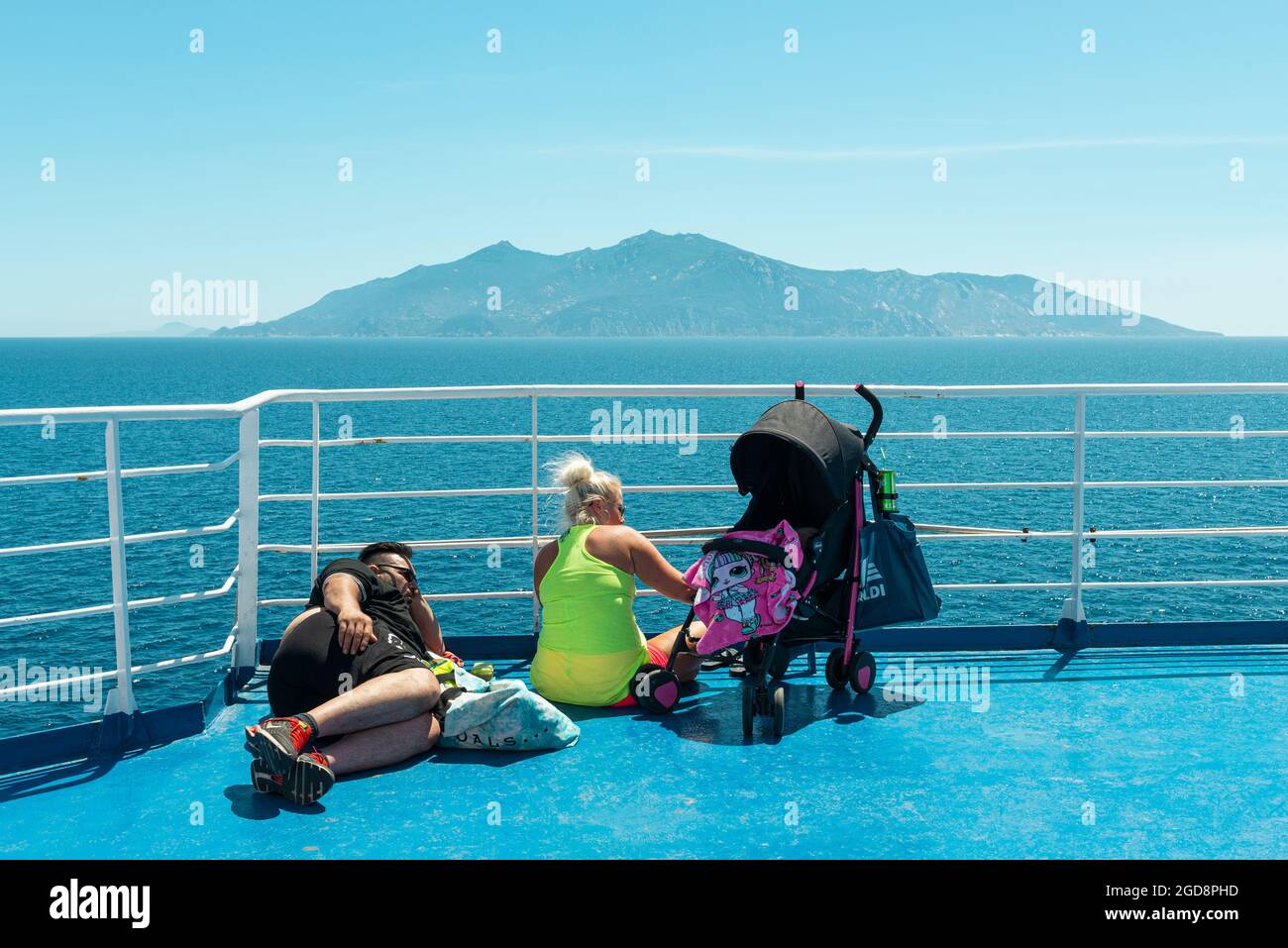 Una famiglia che prende il sole sul ponte di un traghetto per auto al largo dell'isola d'Elba nel Mar Tirreno, Toscana, Italia. Foto Stock