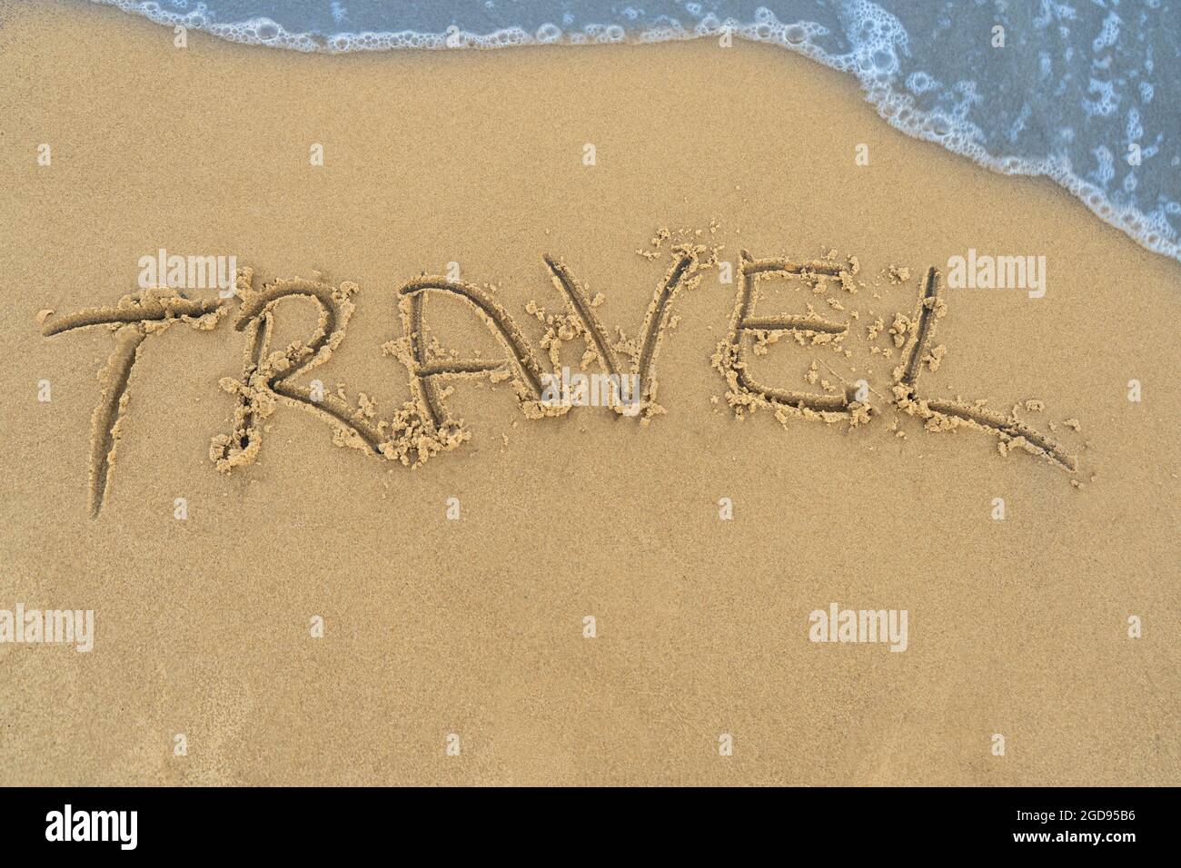Concetto di viaggio - iscrizione nella sabbia. La costa sabbiosa del mare. Motivazione. Onda dell'oceano. La parola viaggio è scritta sulla spiaggia di mare. Vacanze su Foto Stock