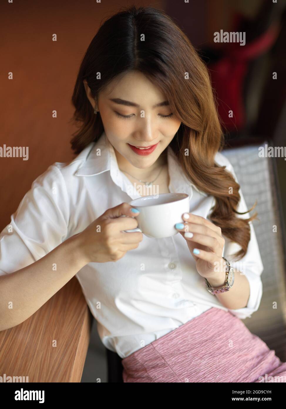 Felice bella donna d'affari tranquilla sensazione di comfort con la sua pausa caffè a mezzogiorno, odore e godere con il suo caffè alla sua scrivania, femmina tenendo c Foto Stock