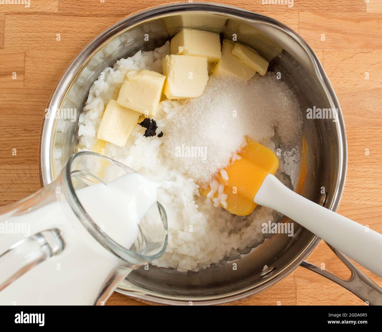 Cucinare il budino. Versare il latte, aggiungere il burro e lo zucchero. Foto Stock