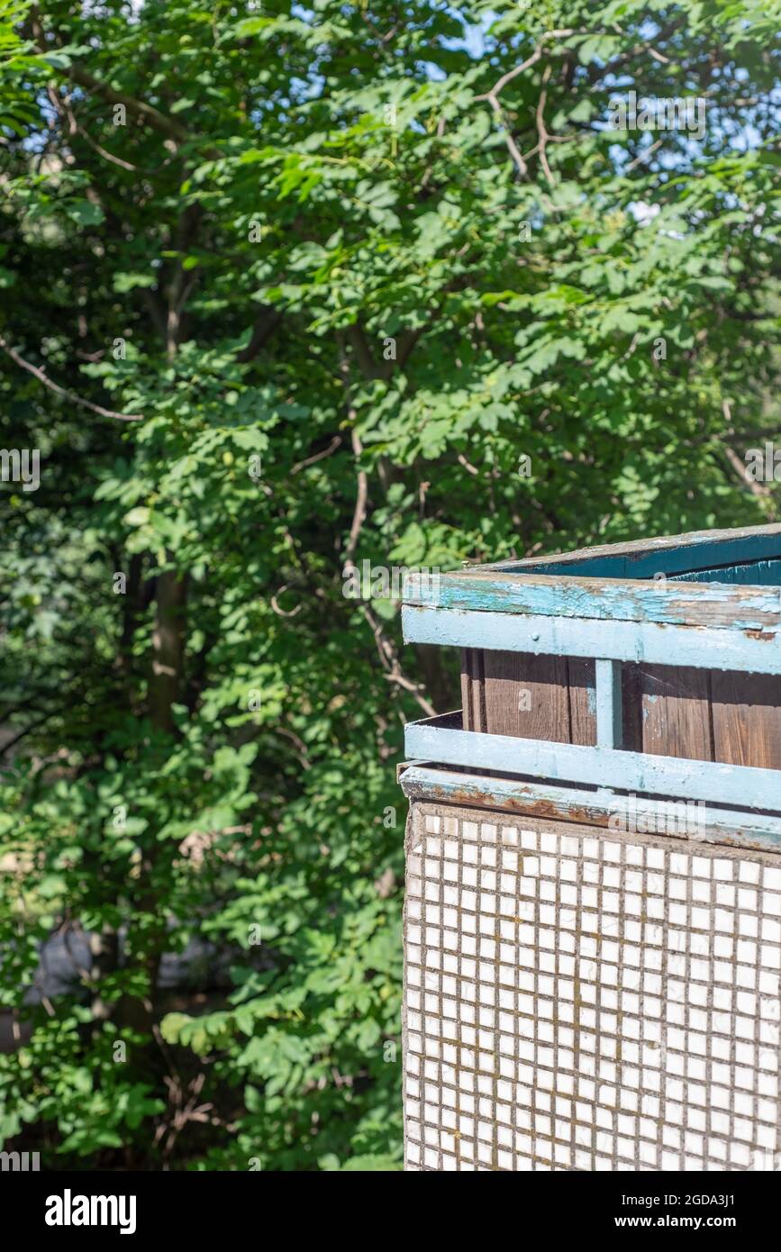 angolo di un vecchio balcone, rivestito di piccole piastrelle in ceramica mosaico, su uno sfondo di alberi verdi. Foto Stock