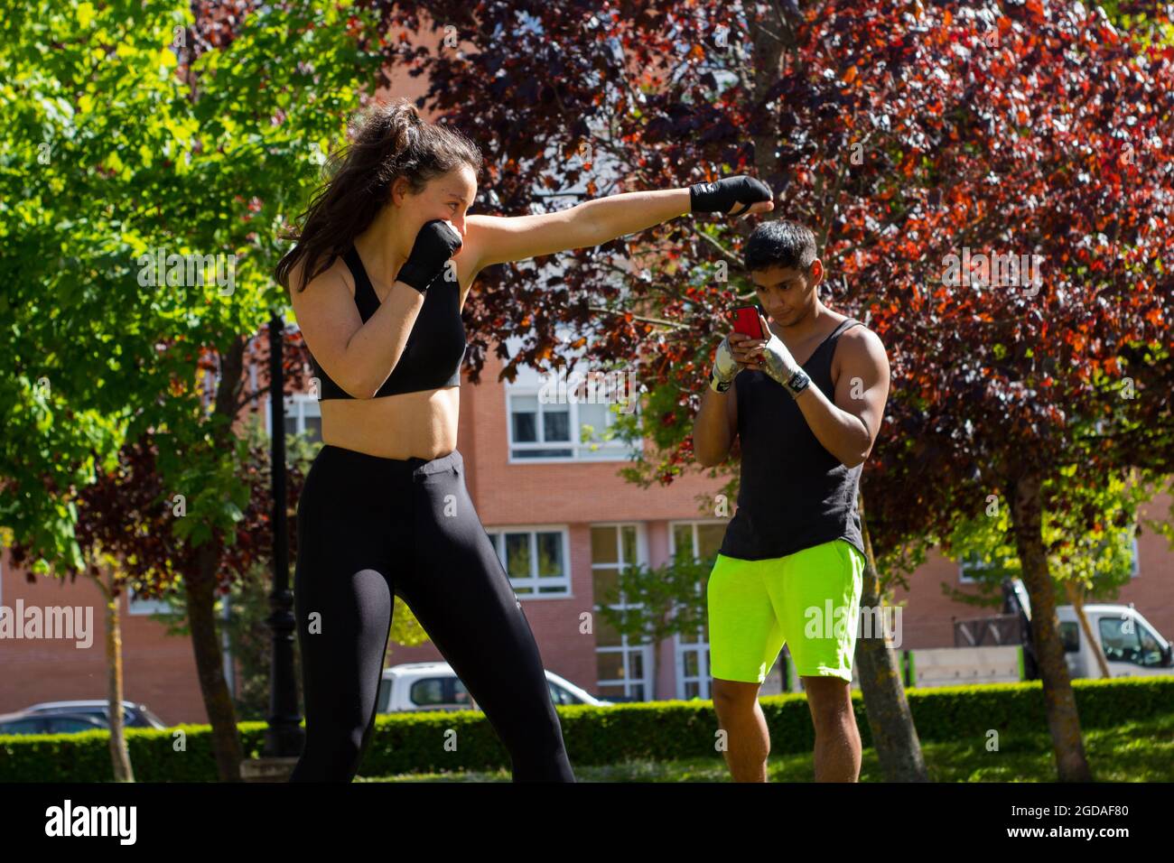 Giovane donna che pugilato atleta con il suo personal trainer nel parco in preparazione per una gara Foto Stock
