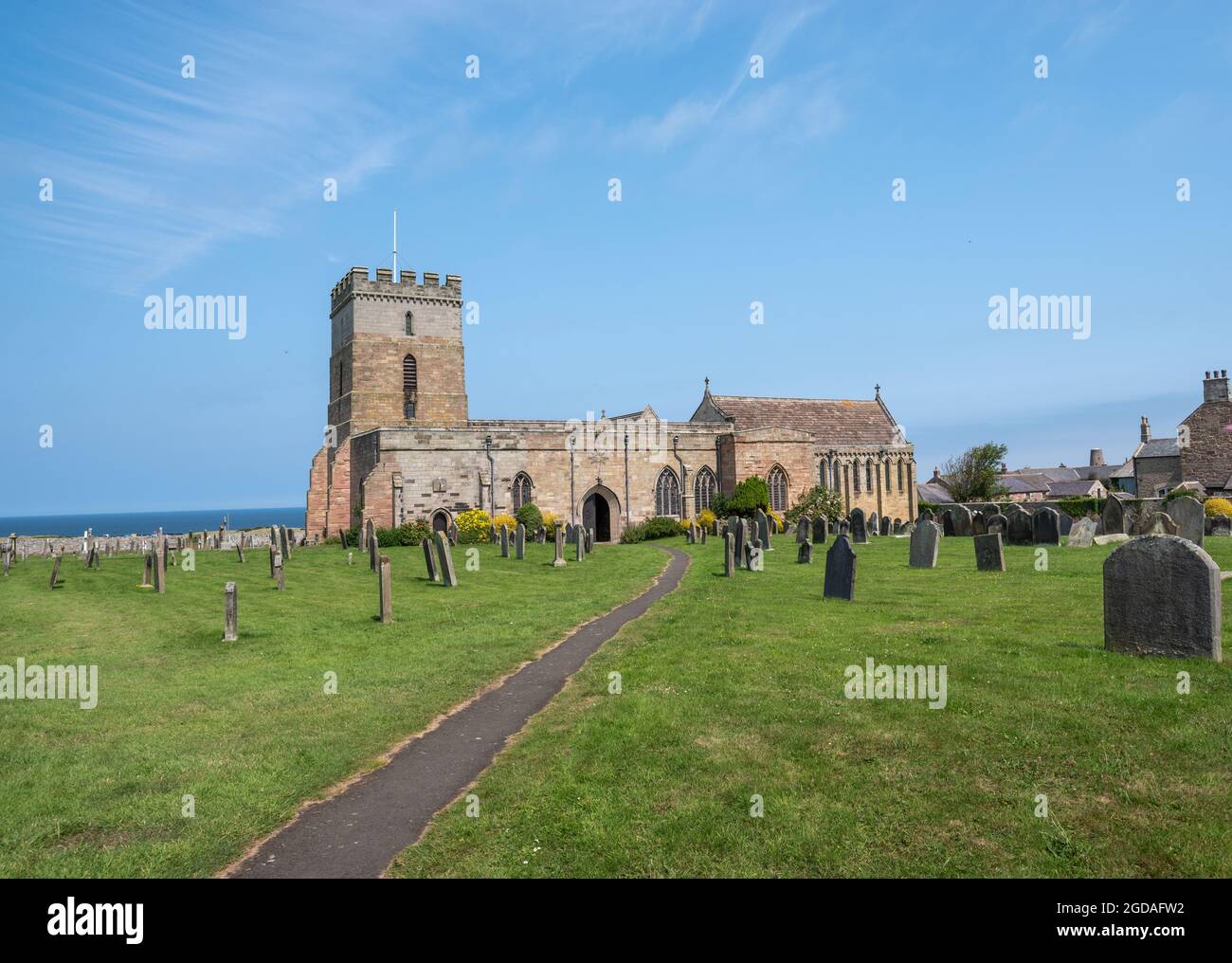 Bamburgh, Northumberland, Regno Unito, 21 luglio 2021 - Chiesa di St Aidens e cimitero in giornata di sole con cielo blu. Foto Stock