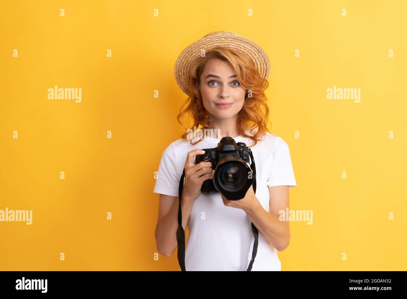 sorridente fotografo donna rossa con fotocamera in cappello di paglia fare foto, fotografia Foto Stock
