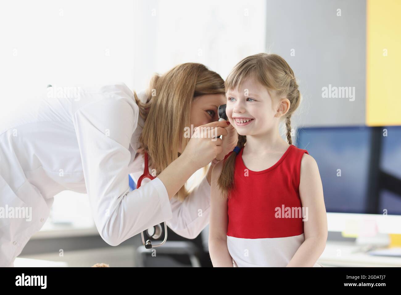 Donna pediatra esame orecchio di bambina con otoscopio in clinica Foto Stock