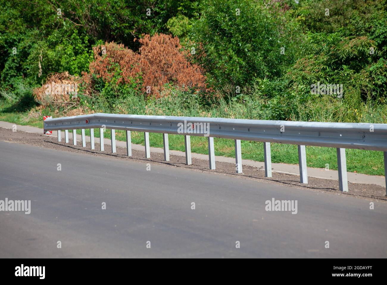 riflettori stradali rossi lungo la strada. recinzioni stradali in metallo di tipo barriera, primo piano. Sicurezza stradale e stradale. Vernice riflettente sul cartello. Barriera mediana Foto Stock