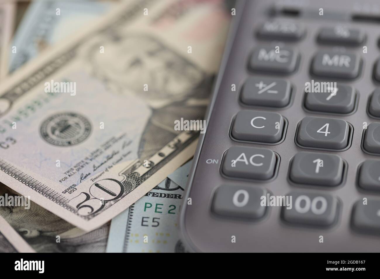 Calcolatrice grigia giacente sulla closeup delle fatture del dollaro Foto Stock