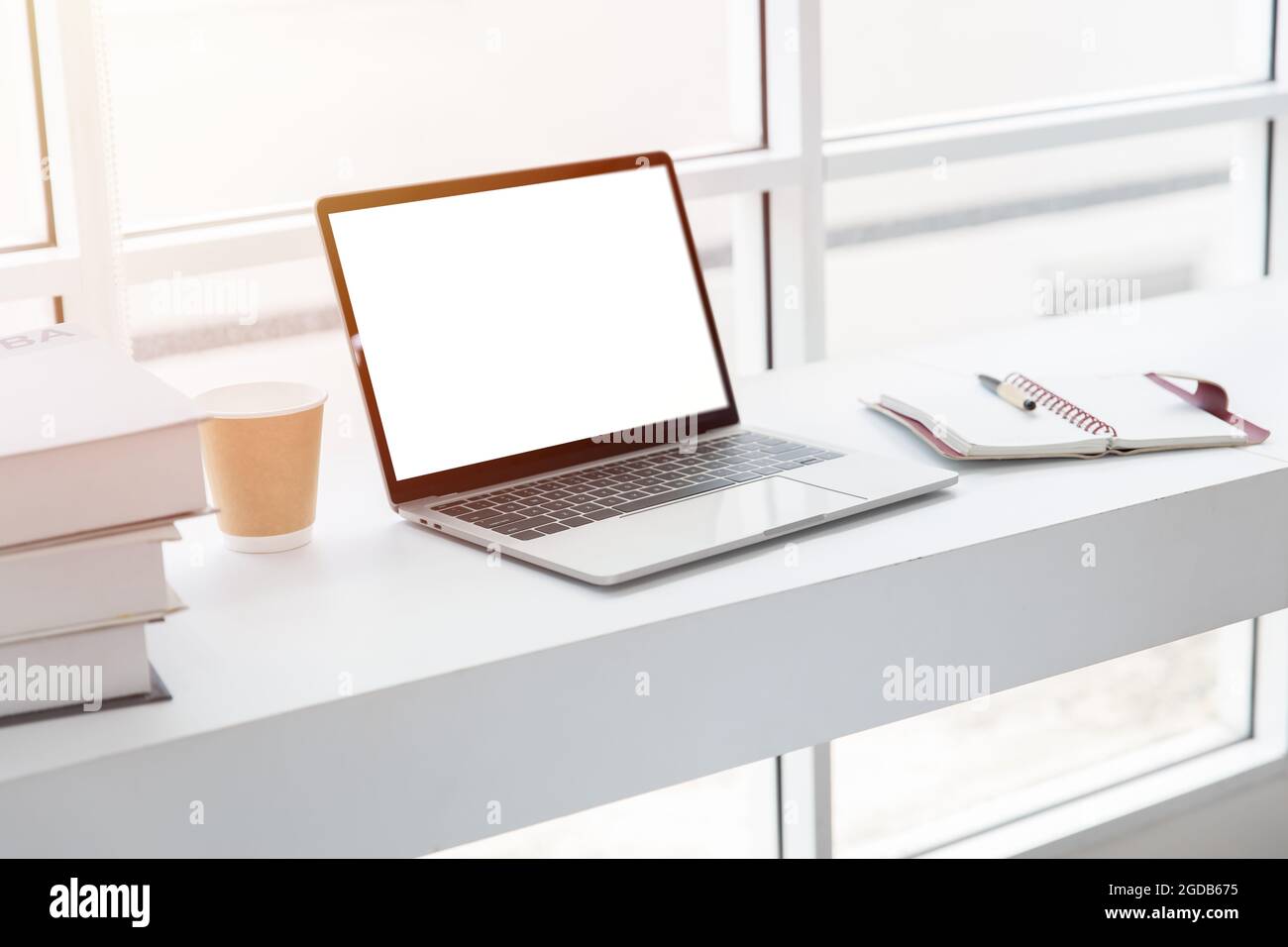 Computer portatile schermo vuoto su bianco pulito tavolo da lavoro accogliente scrivania spazio di lavoro in caffetteria. Foto Stock