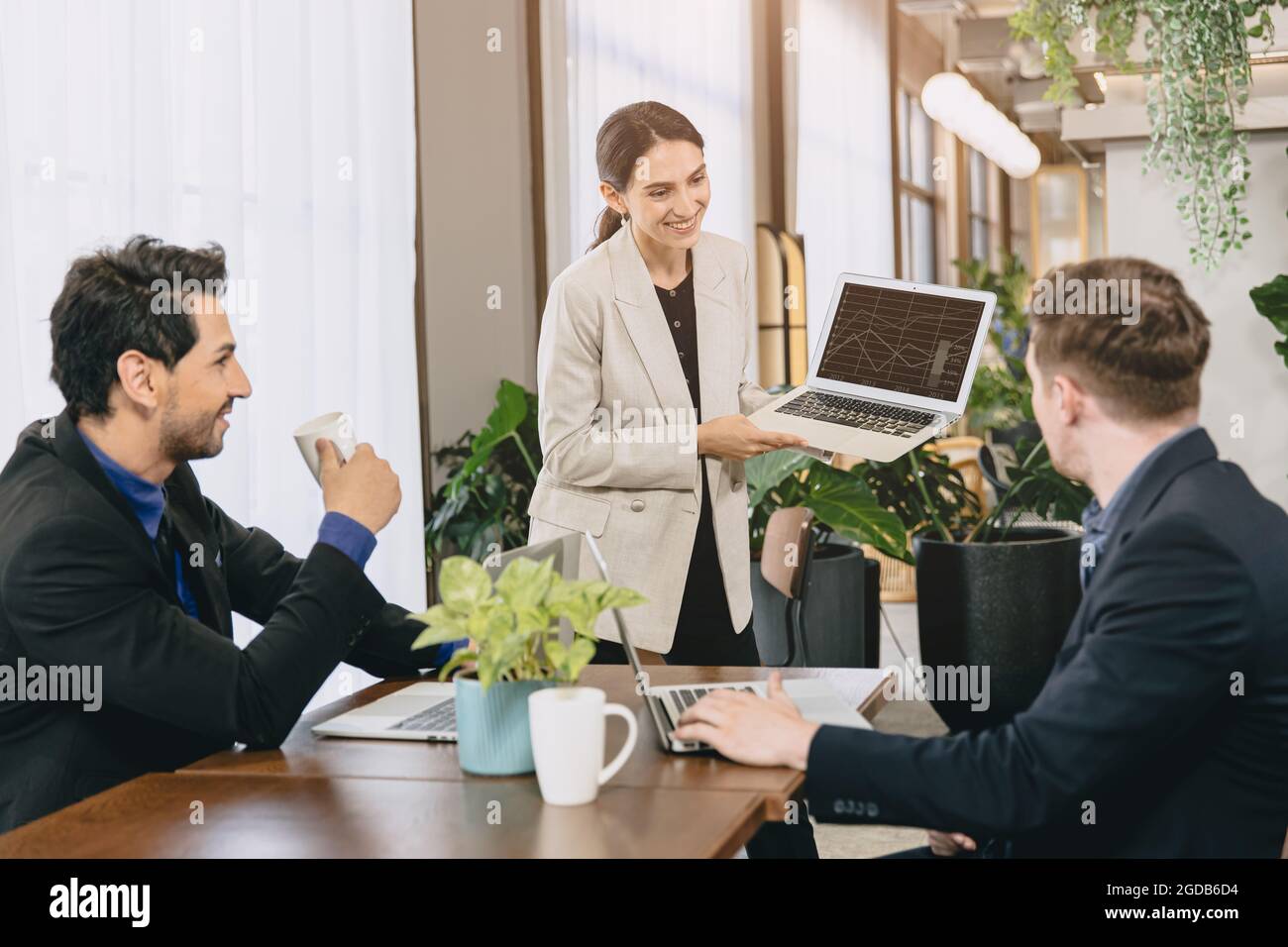 Donne intelligenti felice presentazione del suo lavoro o presentatore di risultati di lavoro al lavoro di squadra maschile in una moderna sala riunioni d'ufficio. Foto Stock