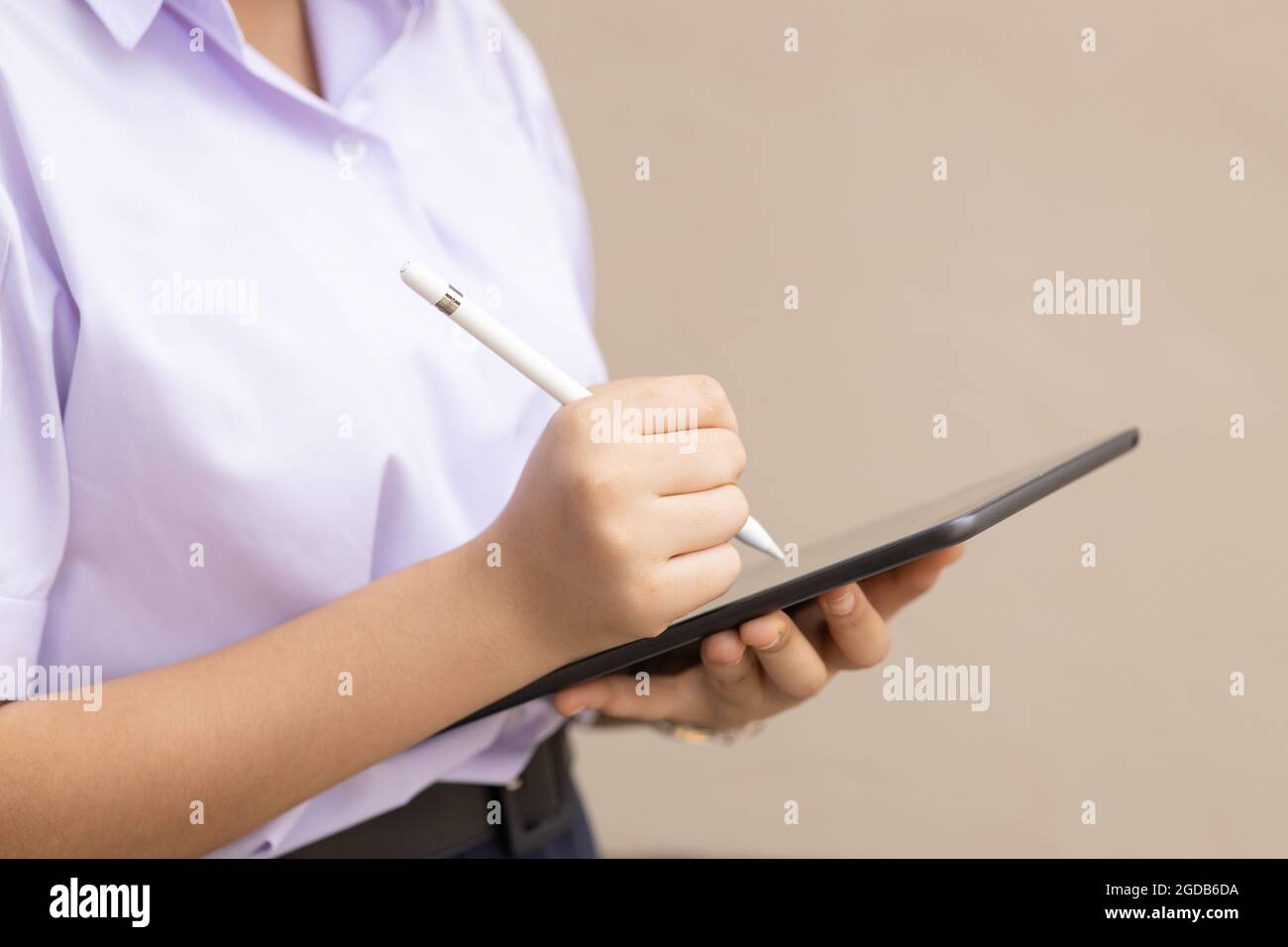 Closeup uniforme scuola studentesca utilizzando Tablet PC e penna stilo per l'istruzione con spazio per il testo. Concetto di dispositivo intelligente per l'innovazione senza carta. Foto Stock