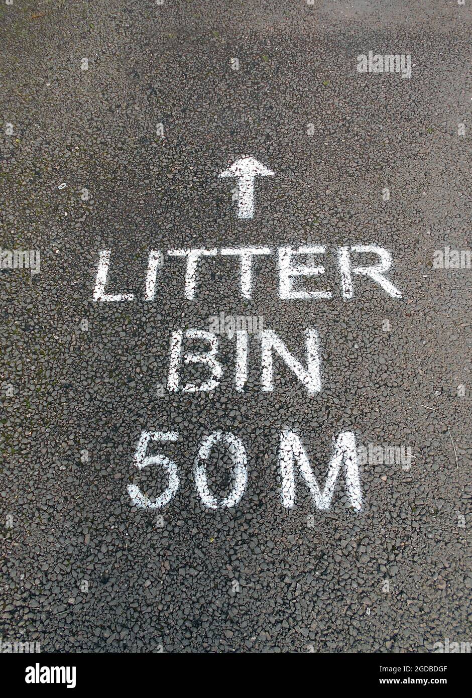 Indicazioni per raggiungere la più vicina pattumiera è stata dipinta a terra, in un parco di Glasgow, per incoraggiare le persone a mettere i loro rifiuti nel bidone. Foto Stock