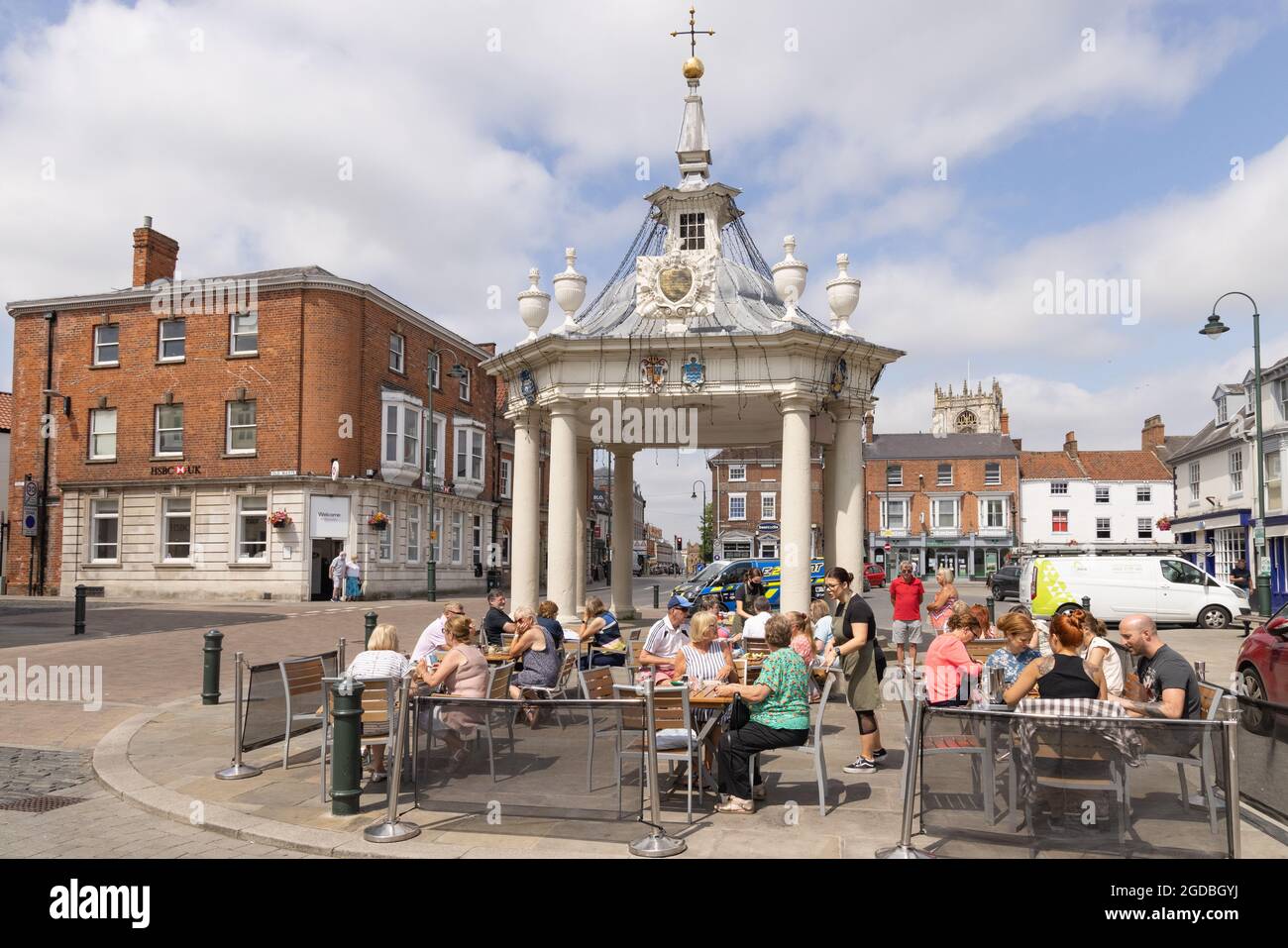 Street scene Beverley Yorkshire; persone che siedono intorno al 19 ° secolo Market Cross nella piazza del mercato, il centro della città, Beverley Inghilterra UK; Foto Stock