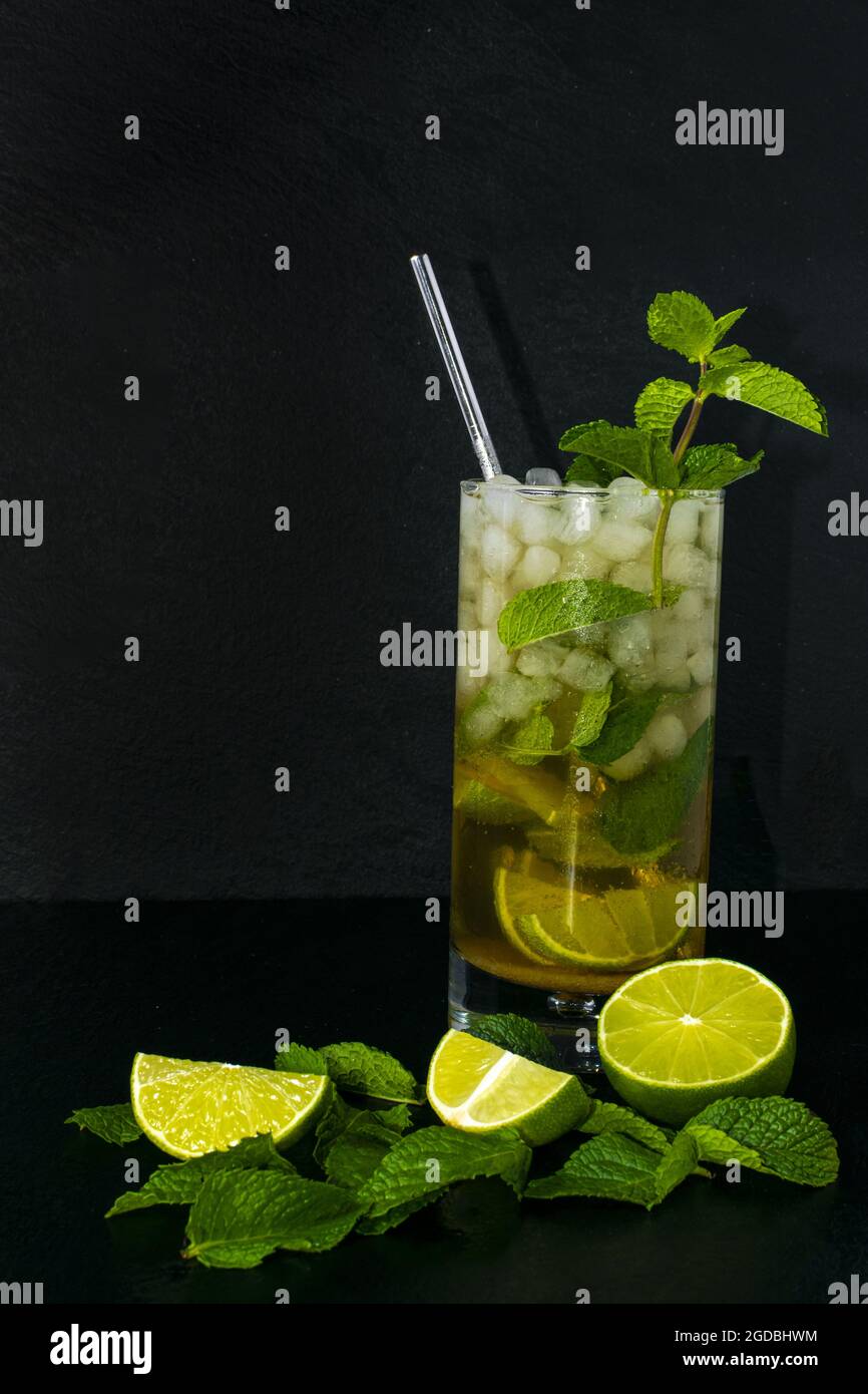 Un primo piano di ingredienti freschi per preparare un cocktail Mojito isolato su sfondo scuro Foto Stock