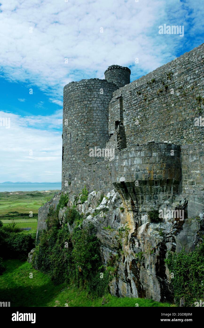 Harlech castello, Galles. Mura difensive imponenti e suggestive. Scatto verticale con sfondo blu per lo spazio di copia. Sito patrimonio dell'umanità dell'UNESCO. Foto Stock