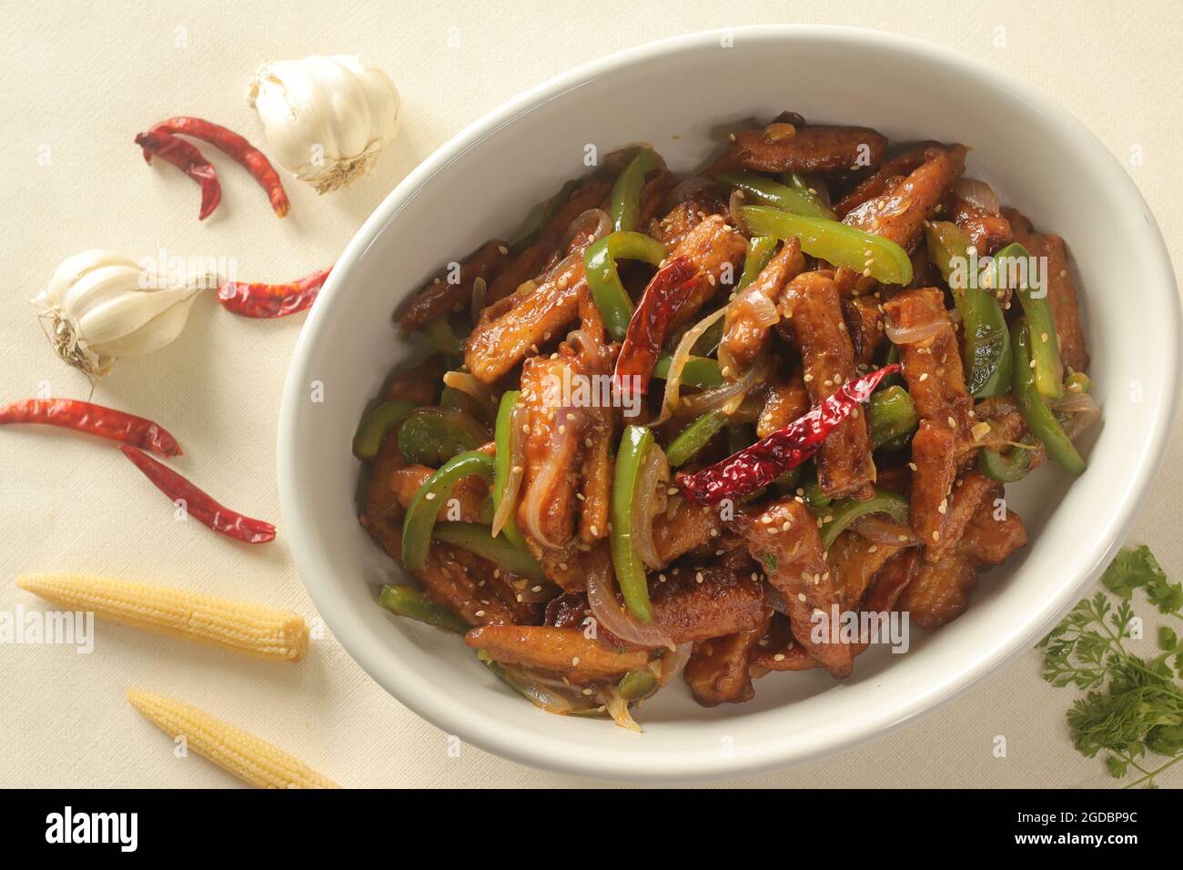 Baby mais manchurian. Croccante mais fritto in salsa manchuriana con peperoni e cipolle. Scatto su sfondo bianco Foto Stock