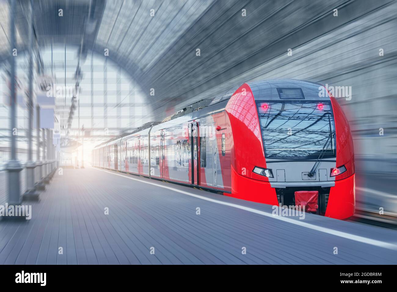 Il treno ad alta velocità si muove velocemente lungo la piattaforma al tramonto. Foto Stock