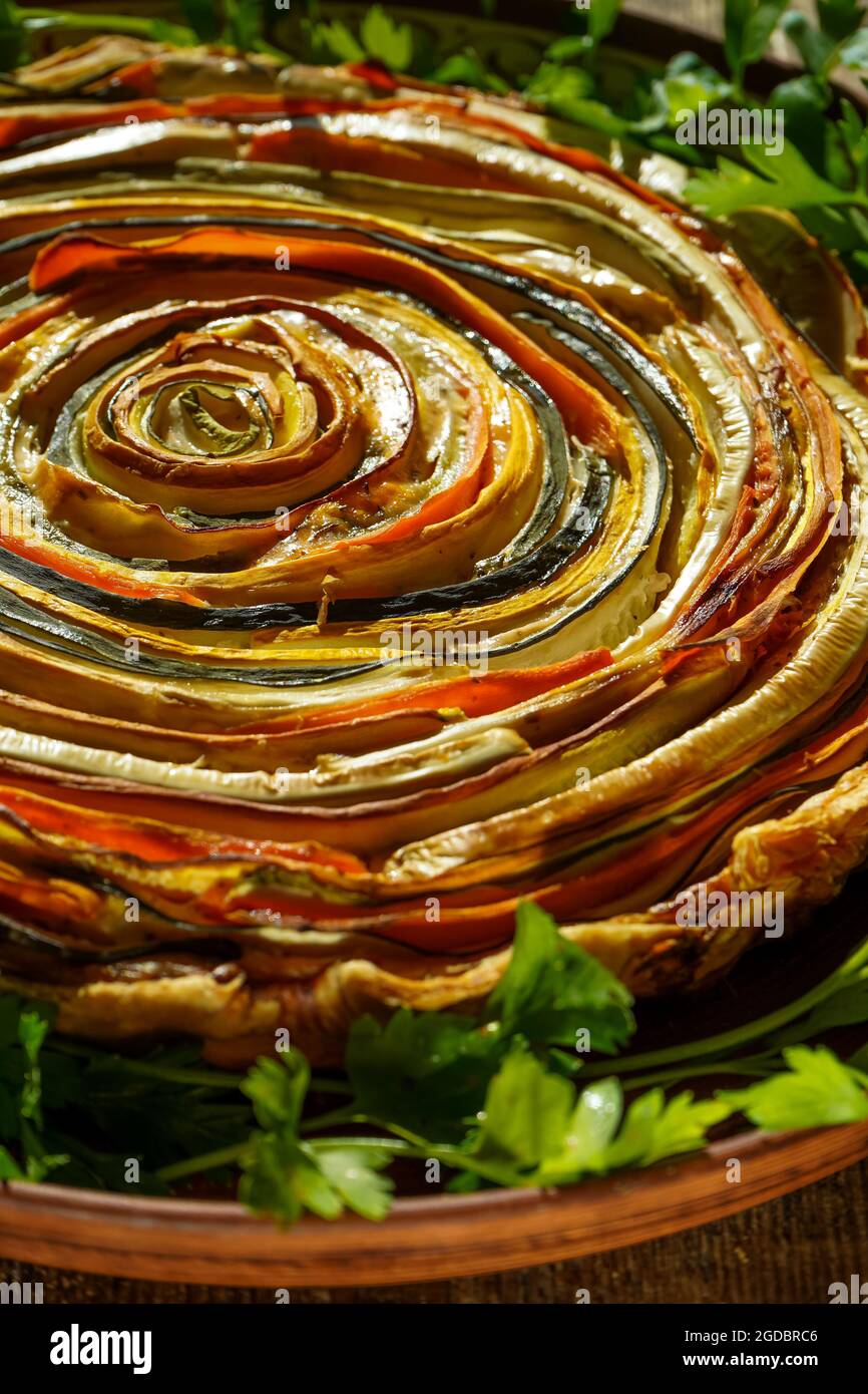 Torta di verdure al sole messicano. Torta aperta rotonda a base di zucchine, melanzane e carote. Vista dall'alto in primo piano. Cibo vegetale sano. Vegetarianismo. Spirale Foto Stock