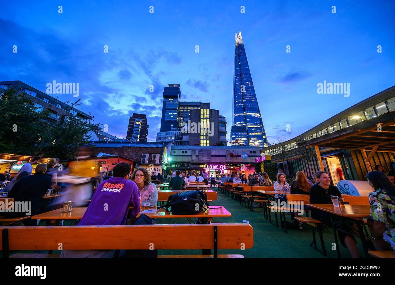 Acetle Yard è un bar all'aperto vicino a London Bridge, Londra, Regno Unito. I clienti potranno gustare un drink al posto a sedere all'aperto subito dopo il tramonto. Lo Shard è alle spalle. Foto Stock