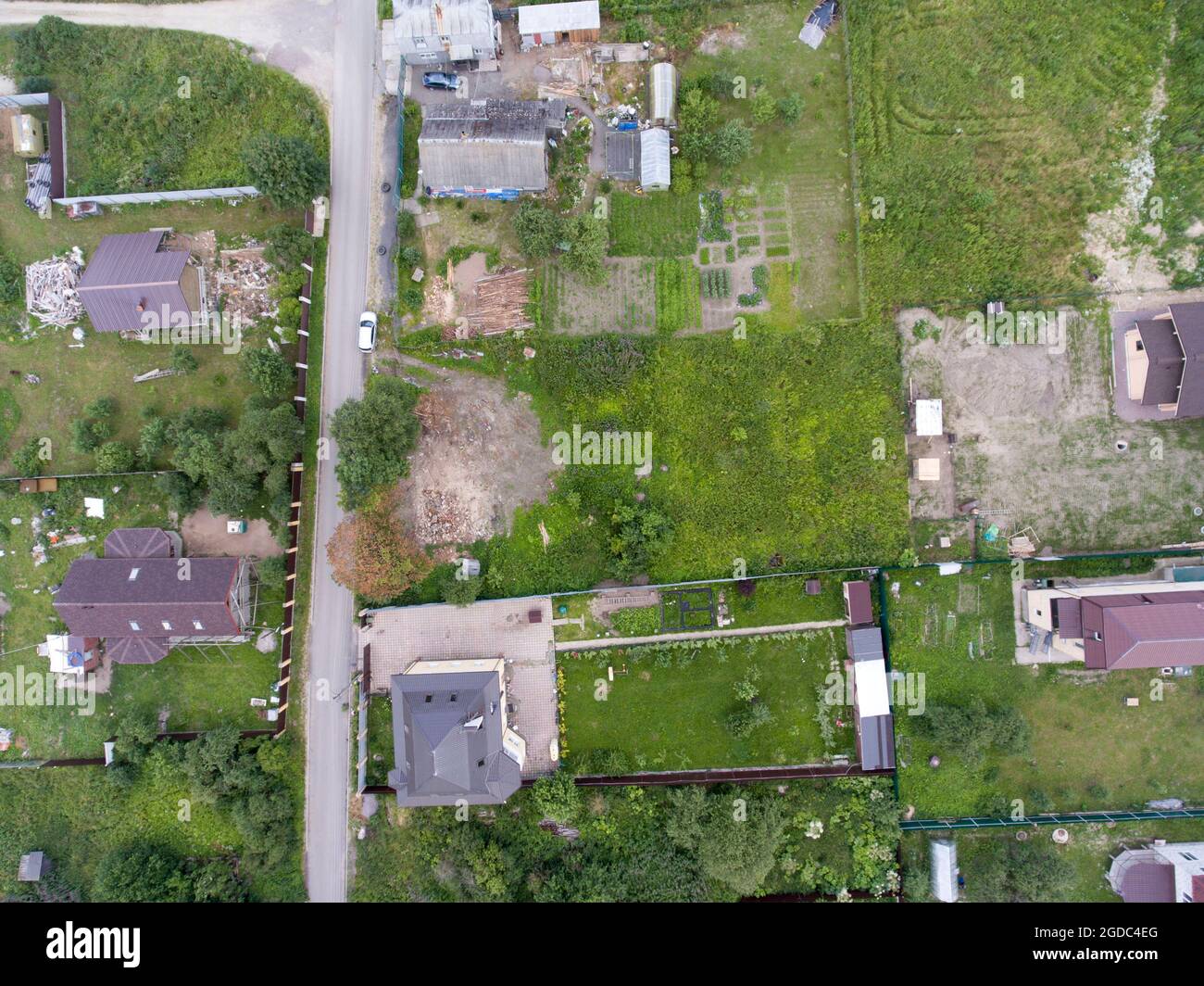 Vista dall'alto in un villaggio con case rurali e terreni verdi, strada asfaltata stretta Foto Stock