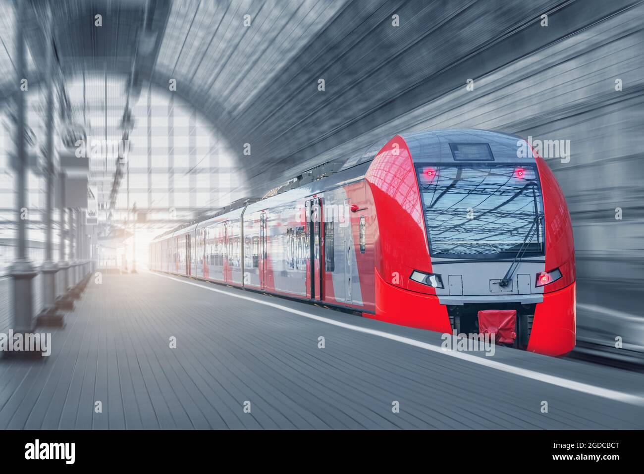 Il treno ad alta velocità si muove dalla piattaforma al tramonto. Foto Stock