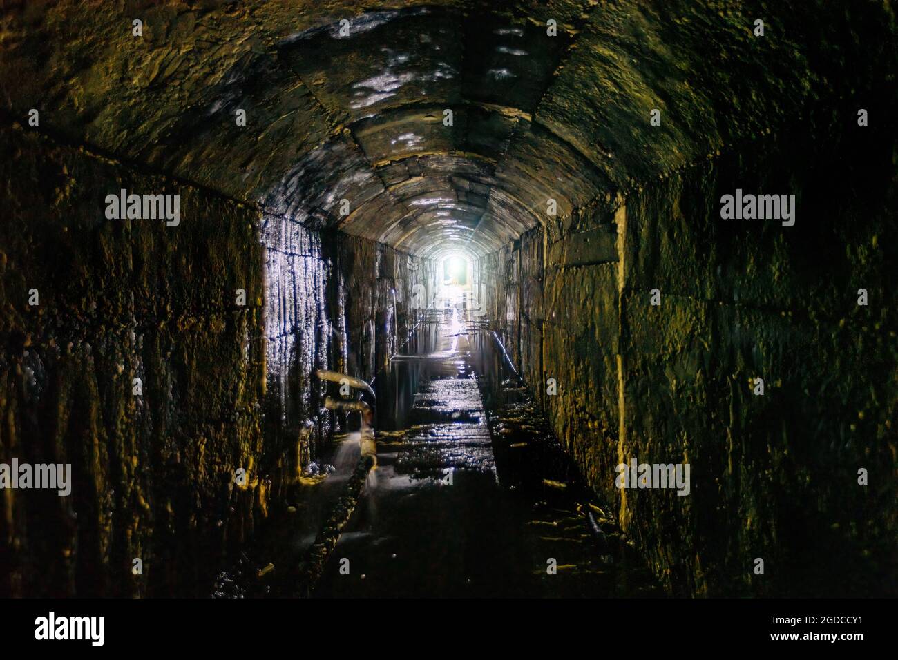 Vecchio tunnel fognario sommerso sotterraneo a volta scura. Foto Stock