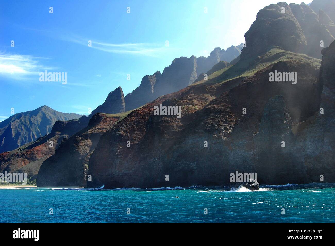 I nuotatori molto piccoli mostrano le immense dimensioni delle montagne Pali sulla costa di Na Pali, Kauai, Hawaii. Foto Stock