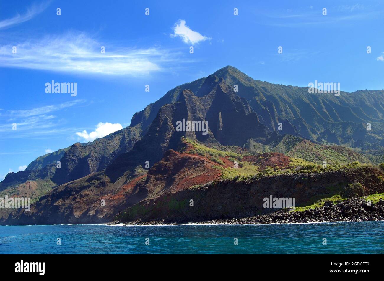 Gli aspri crinali delle montagne Pali sono incorniciati da cieli blu vividi sull'isola di Kauai, Hawaii. Aqua Water abbracciare la Costa Na Pali. Foto Stock