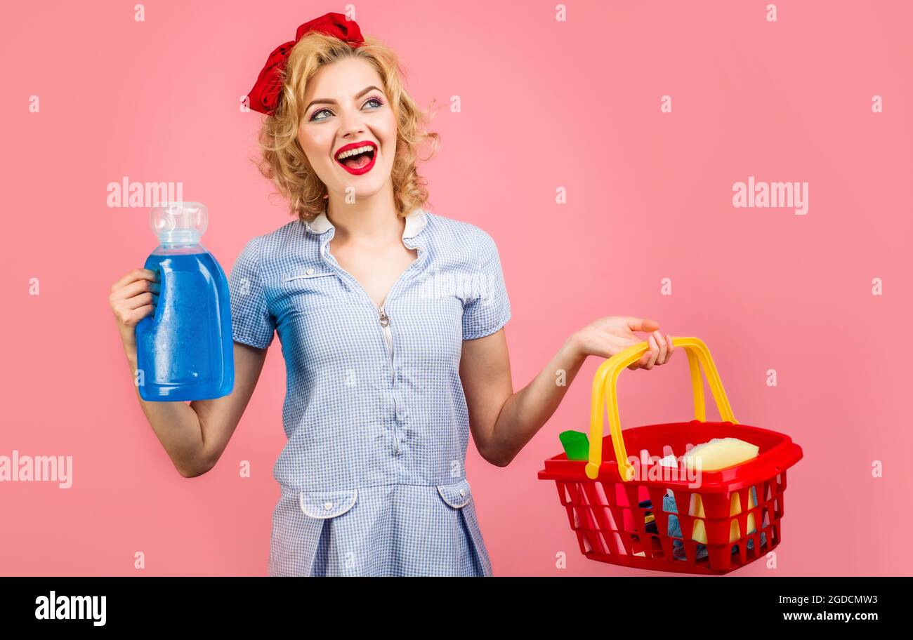 Donna sorridente con prodotti per la pulizia. Il detergente femmina contiene il cestello con i materiali per la pulizia. Le faccende della casa. Foto Stock