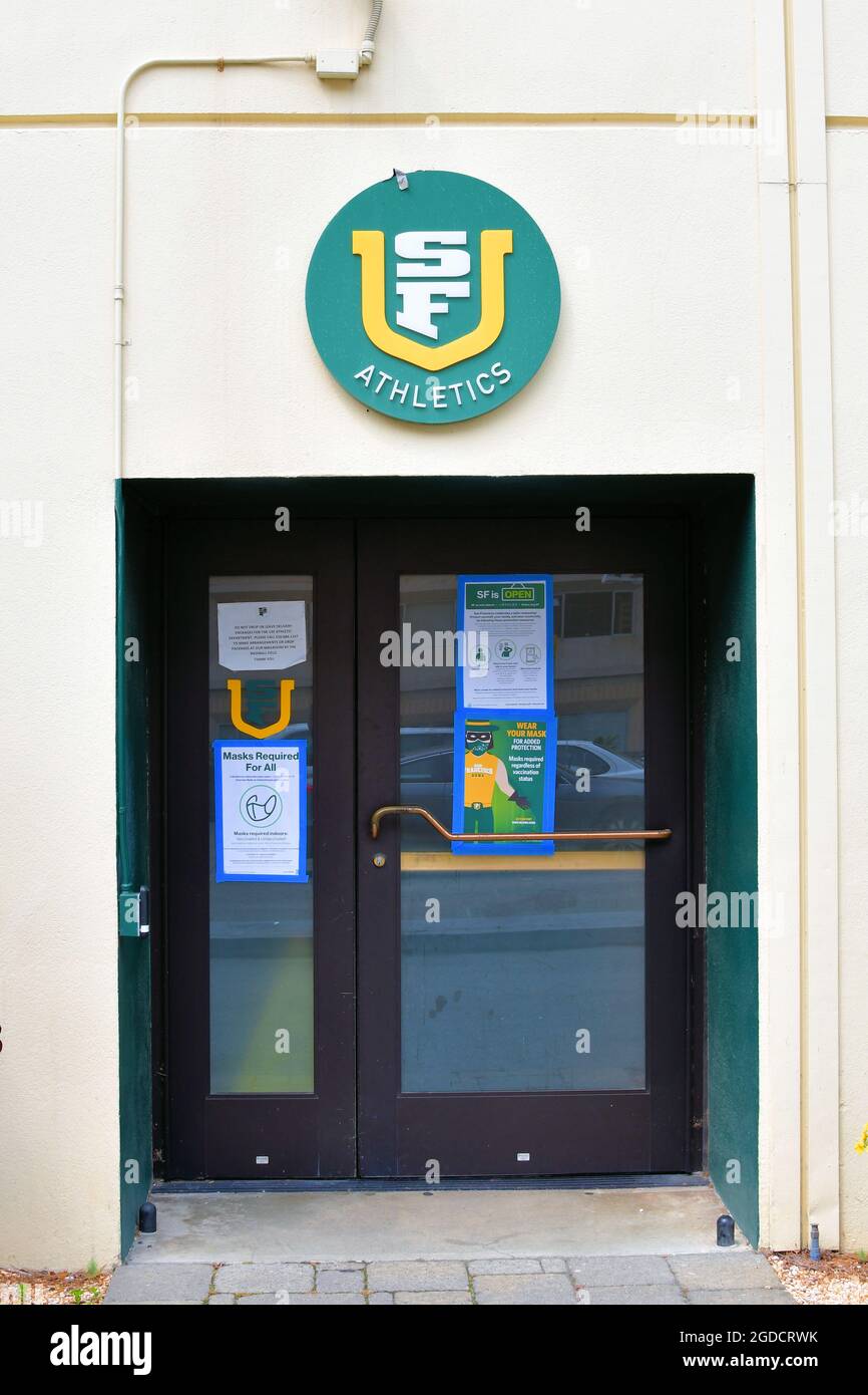 Ingresso a un edificio di atletica della University of San Francisco con logo universitario e restrizioni Covid-19 a porta; San Francisco, California. Foto Stock