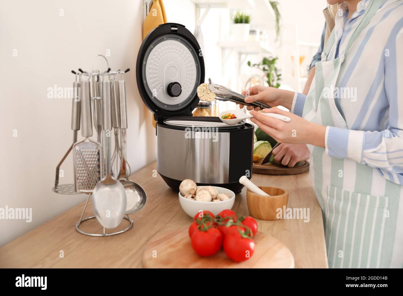 Donna che usa il fornello multiplo in cucina Foto Stock