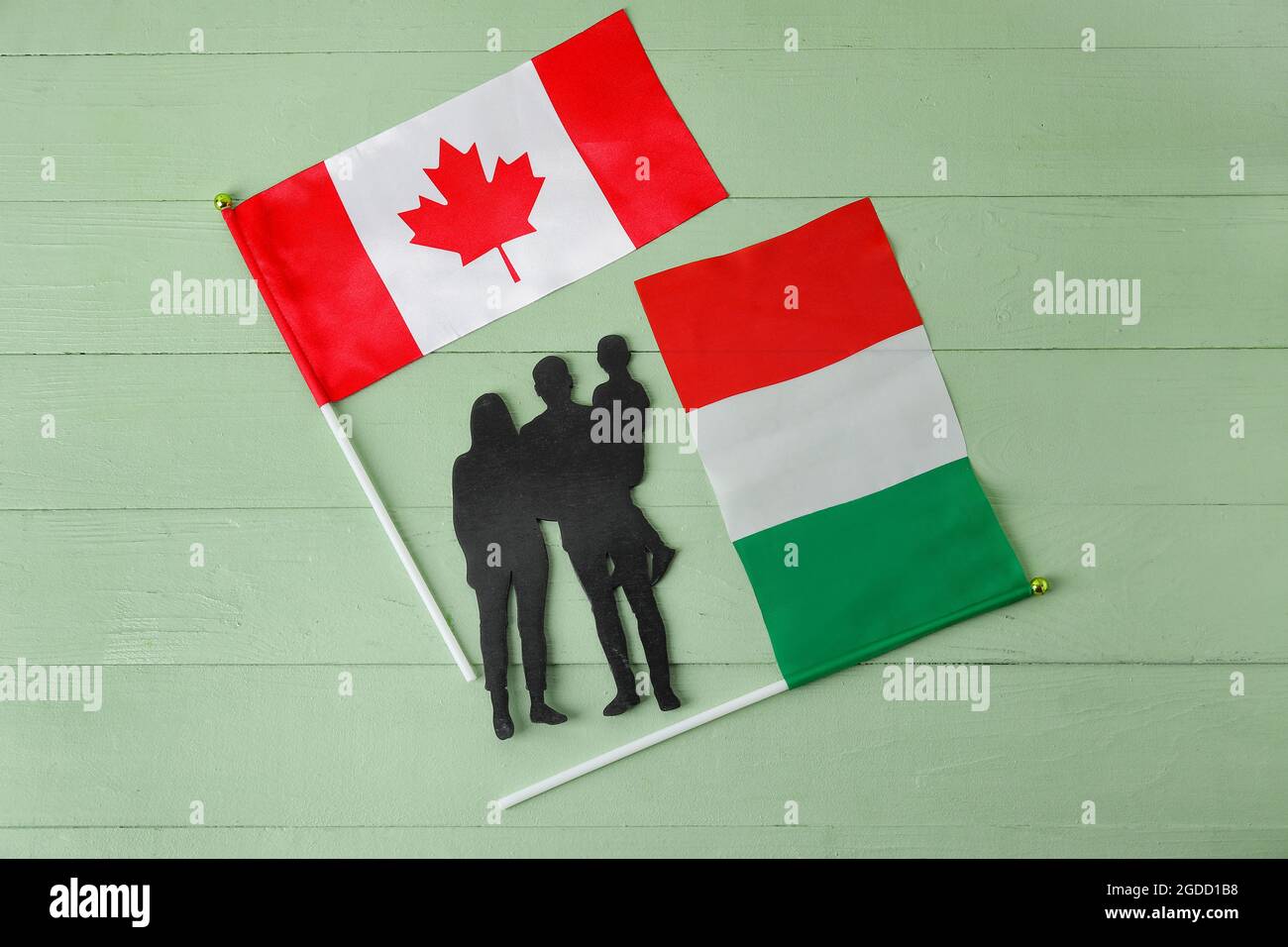 Figura di famiglia e bandiere del Canada e dell'Italia su sfondo di legno colorato Foto Stock