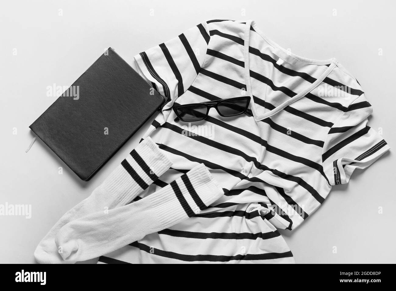 Elegante t-shirt, occhiali da sole, calze e notebook su sfondo chiaro Foto Stock